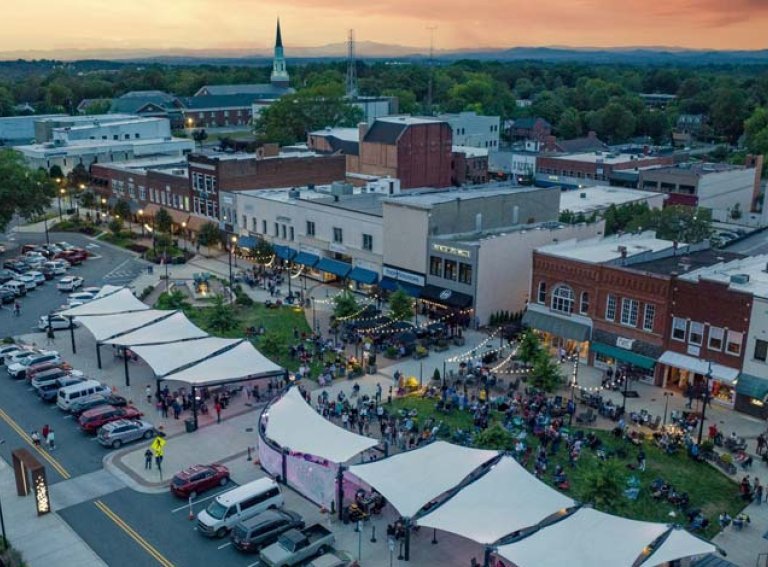 Aerial view of downtown Hickory at sunset with concert on the green by the Sails