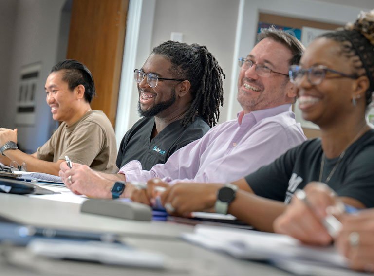 Four smiling graduate students participate in classroom discussion