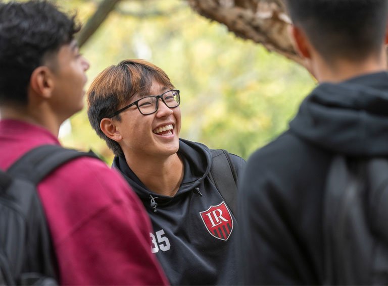 Three students talking on campus between classes