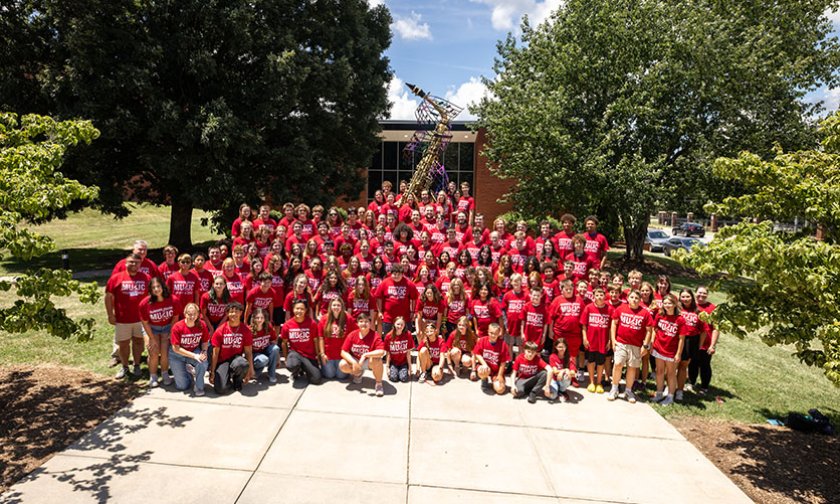 All members of Youth Summer Music Camp in a group in font of Mauney Music Building and the Super Sax statue