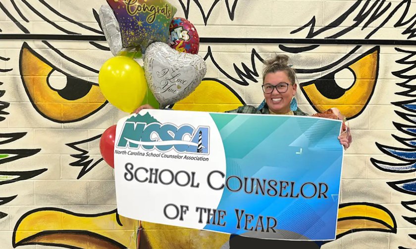 Lauren Mena holds a banner declaring her School Counselor of the Year