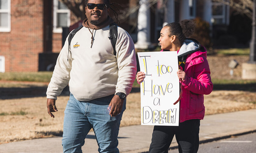 A man and a woman marching on MLK Day 2025, one carries a sign reading "I too have a dream."