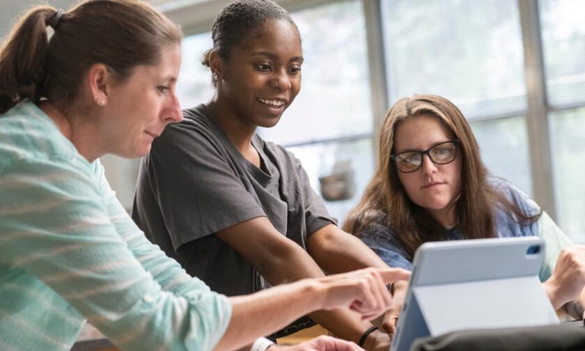 Professor talks with two students in physics lab