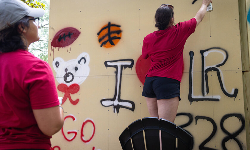 Students spray painting LR-themed images on the graffiti wall