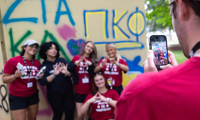 Members of two sororities pose for a photo in front of the graffiti wall