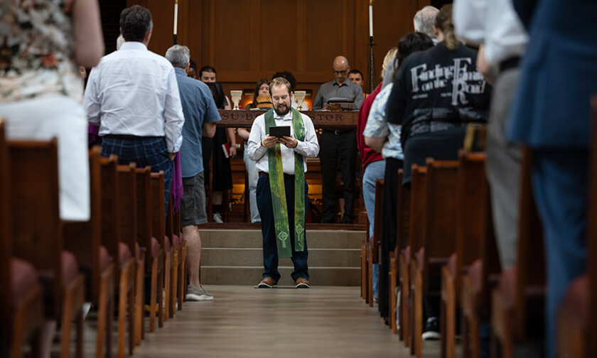 Pastor Vern, framed by congregation, reads during chapel service
