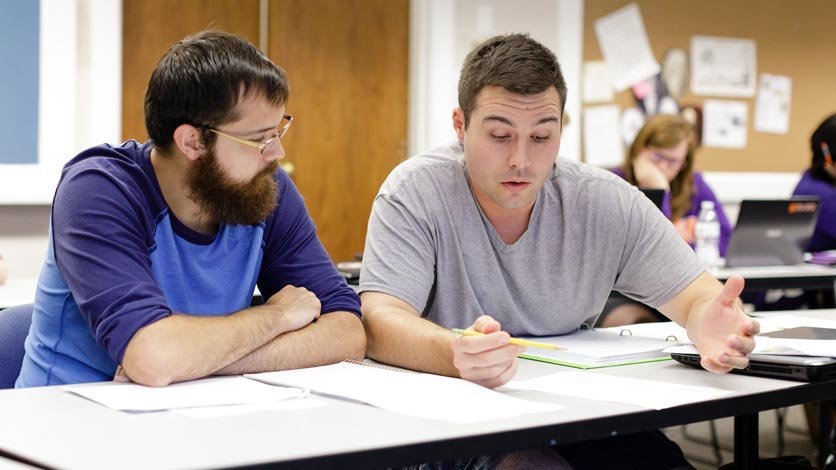 Two seminary students work on class assignment at classroom table