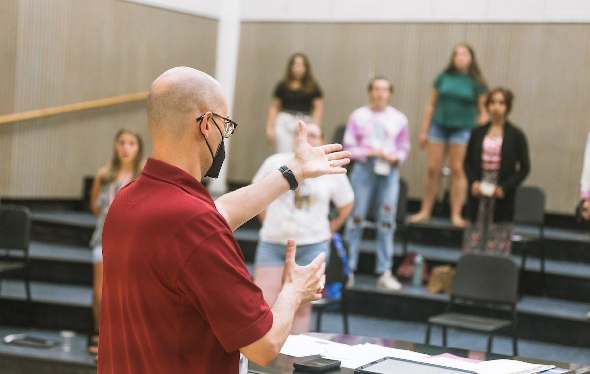 An instructor stands in front of a room of students with his back to the camera