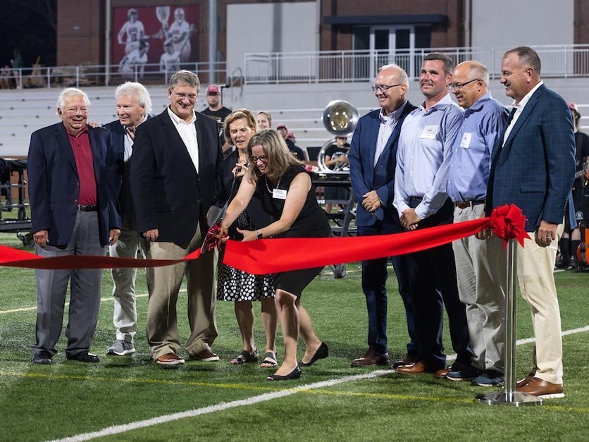 Moretz stadium benefactors and supporters cut a ribbon during ribbon cutting ceremony on field