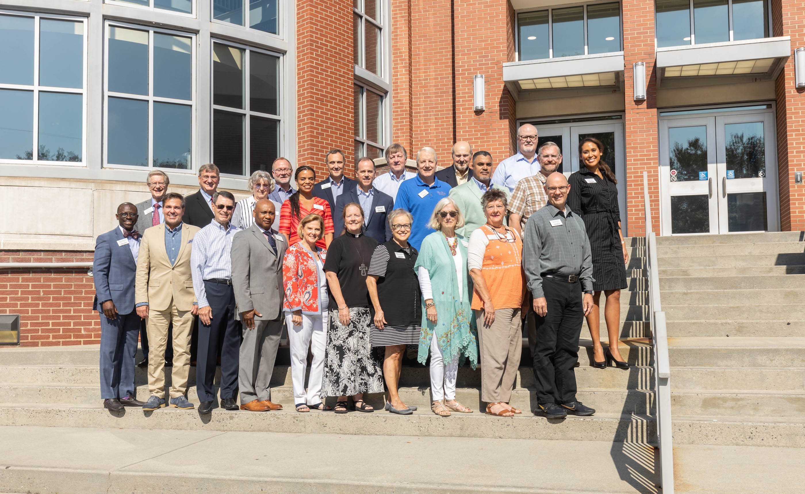 A group of people stand outside of a building on a sunny day