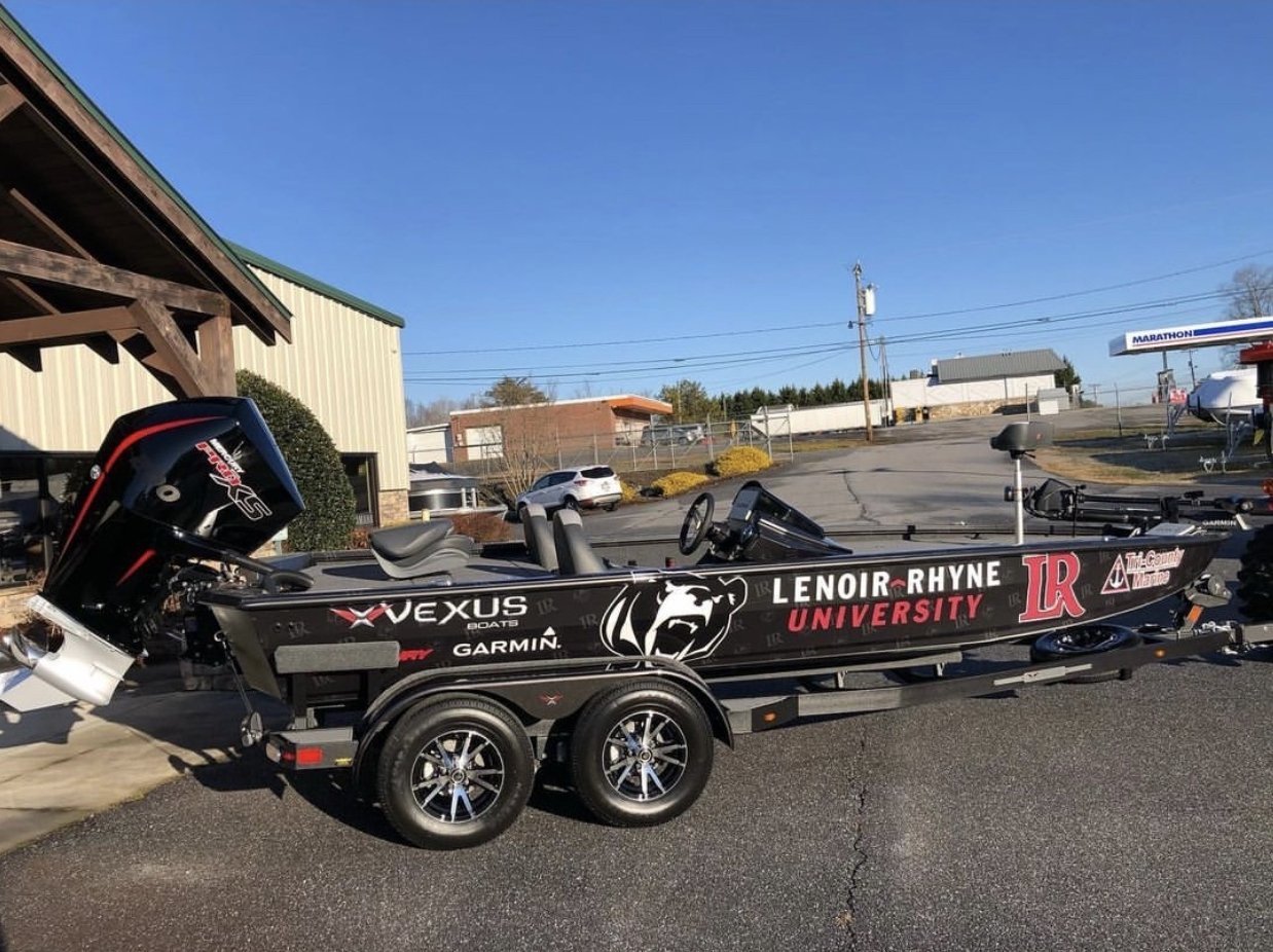 A bass fishing boat sits on a trailer outside