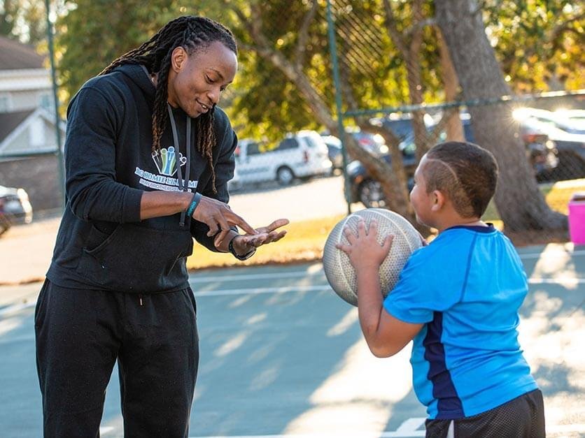 LR alumnus Jamal Stroud talks to a child playing basketball.