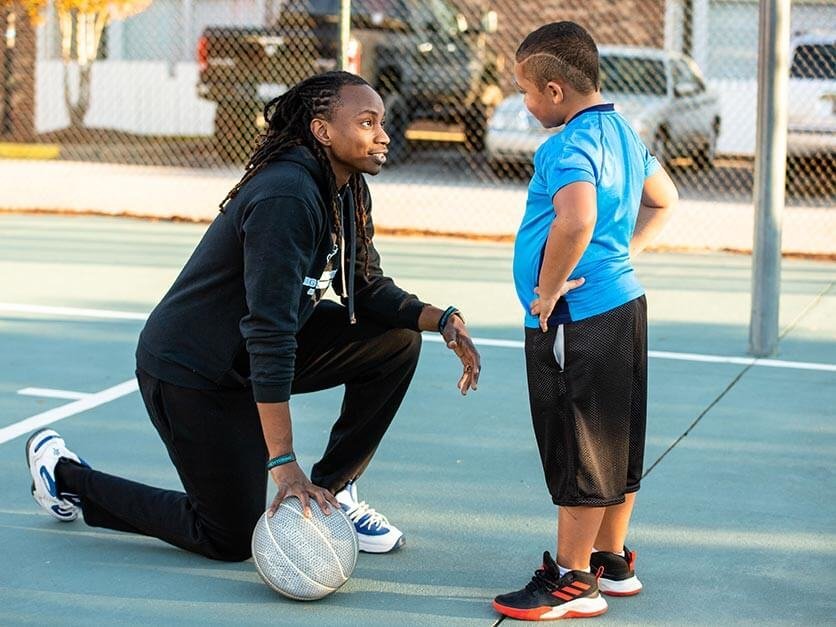 LR alumnus Jamal Stroud talks to a child while playing basketball.