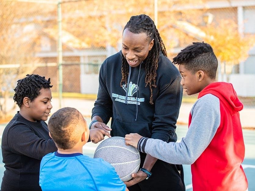 Jamal Stroud playing basketball with children.