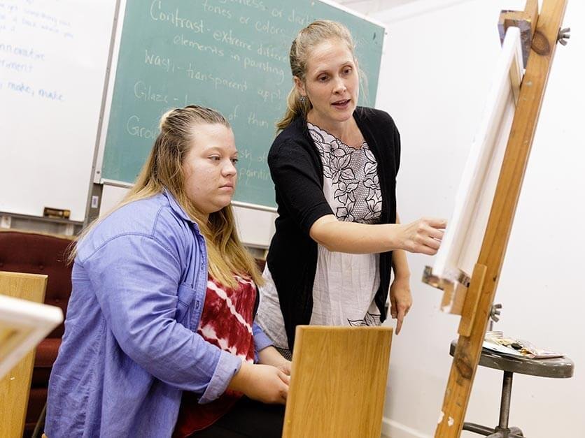 Claire Pope discussing a painting with a student