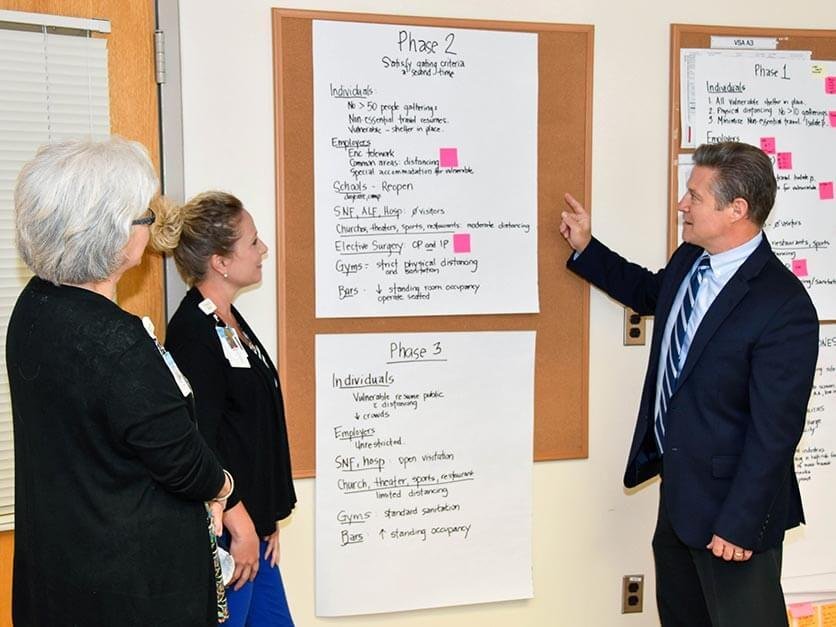 Dr. Lowry pointing out information on a board to colleagues