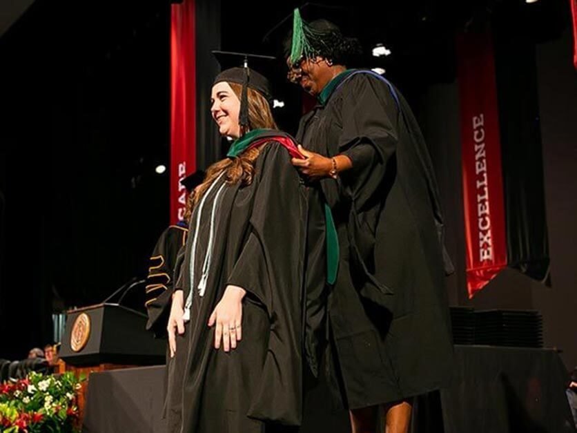 A graduate student is hooded at commencement