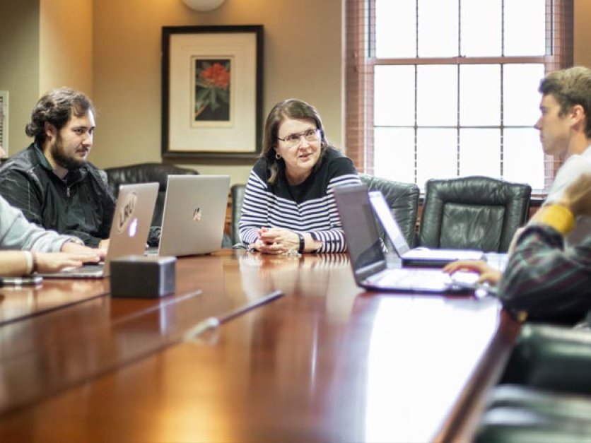 Student investors talk with professor seated around a conference table