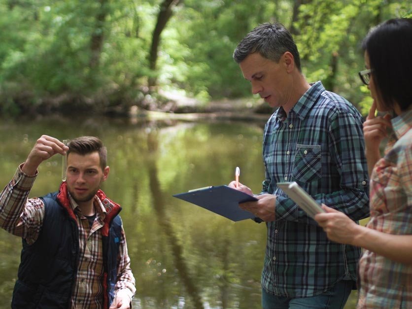 Three people testing water quality of river