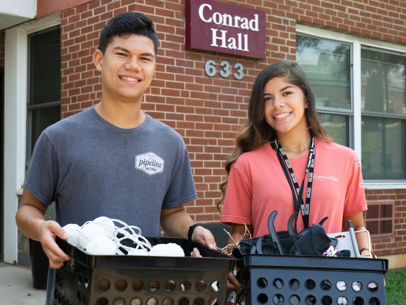 Two students cart boxes into Conrad Hall as part of move in. 