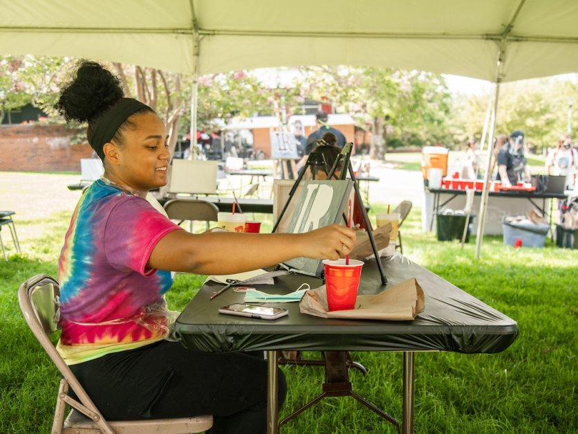 A student sits outside and paints