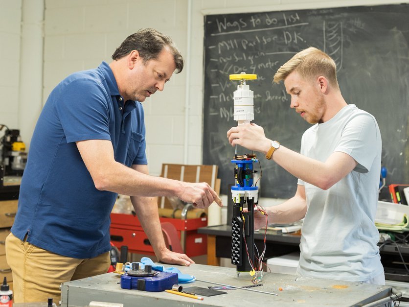 Student and professor work on rocket components in a lab