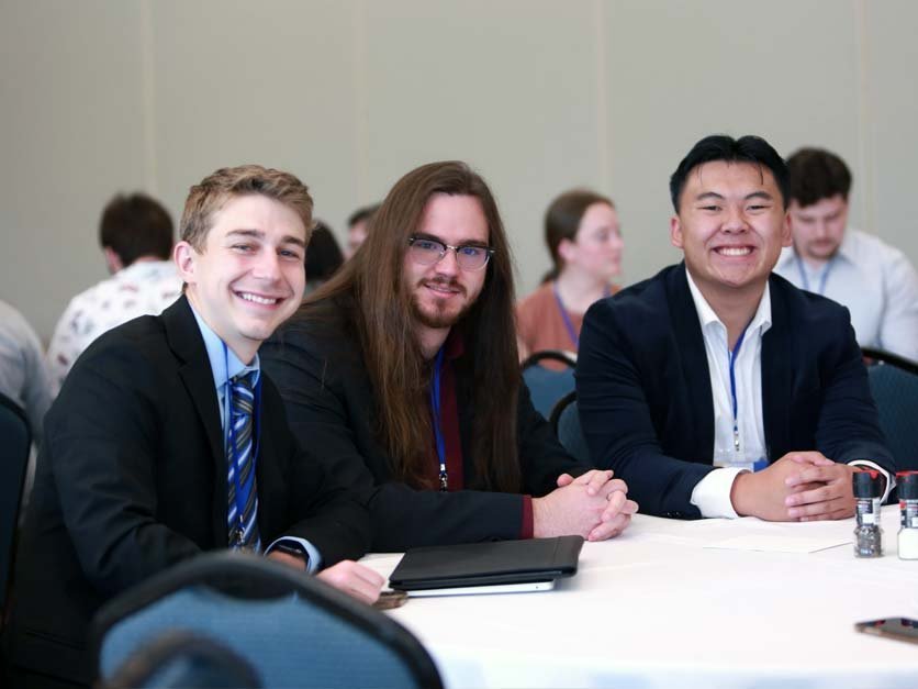 Three students at table attending NCAS meeting