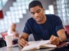 Student working at table and reading from a book