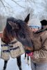 Carly York, right, stands outside in the snow with a horse