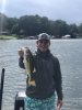 A student stands on a boat and holds out a fish to the camera