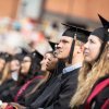 Graduates in crowd listen to speakers on commencement stage