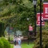 Students walking along campus sidewalk with LR red banners on light posts