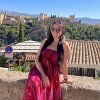 Lina San Juan Martinez sits on a wall with Granada in the background