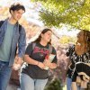 Three students talking while walking across campus