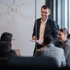Group of coworkers discuss AI project and chart progress on whiteboard