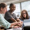 Professor talks with two students in physics lab