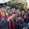Red and black streamers fly over smiling graduates on stadium field