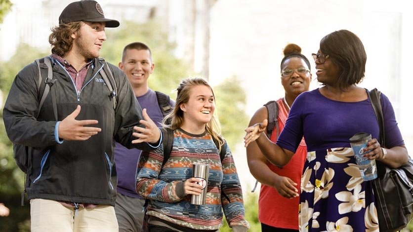 Professor talking and walking with group of students between classes