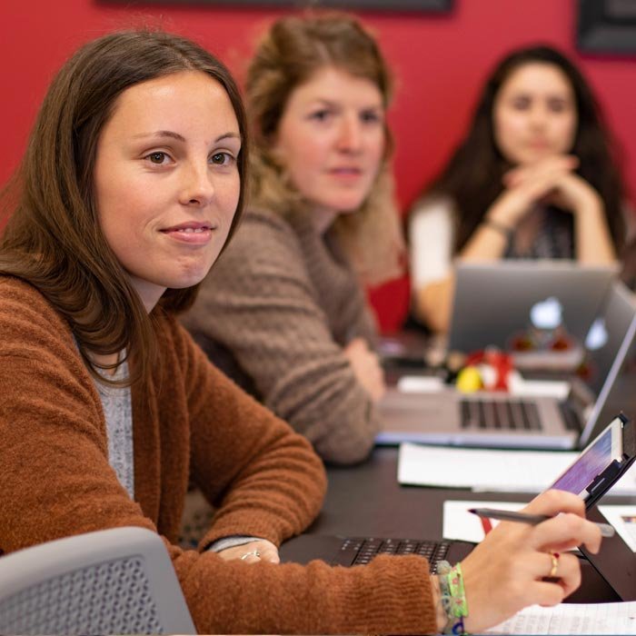 Three students in classroom listening to professor lecture