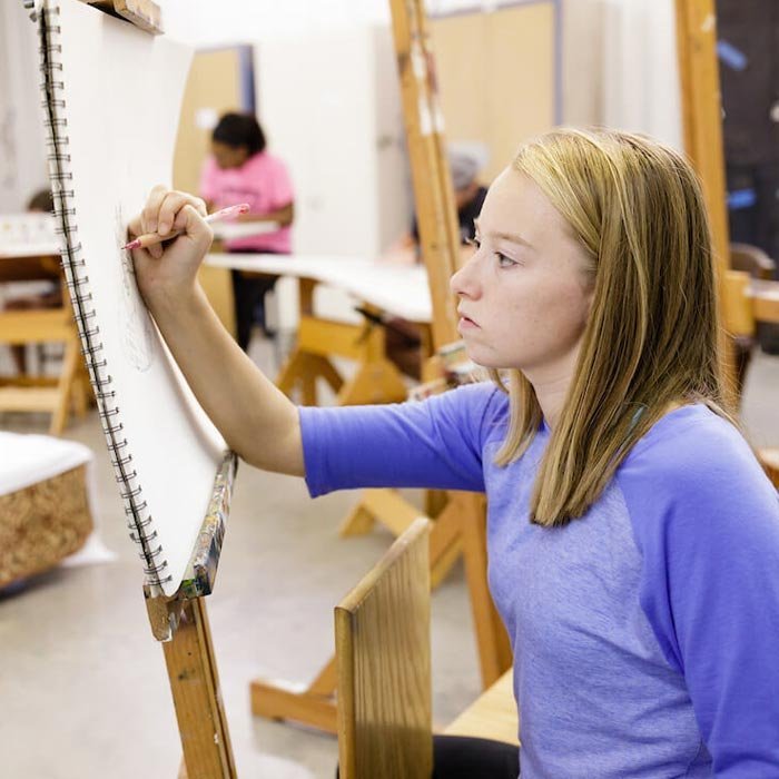 Student working on canvas in art class