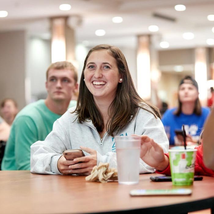 Student smiles while attending an event in the dining hall