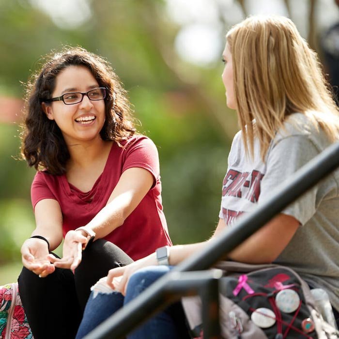 Two students talking on lawn