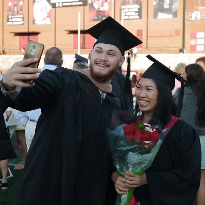 Two students take a selfie at end of commencement ceremony