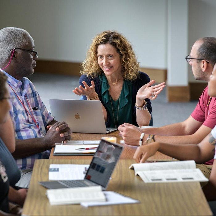 Professor talking with students in seminary classroom during discussion